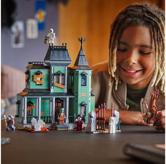 Un garçon regarde un manoir hanté LEGO avec vampire, Frankenstein, squelette, loup et fantôme.