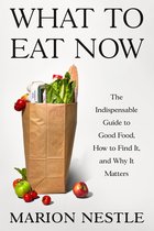 Boek 'WHAT TO EAT NOW' met een bruine papieren tas vol verse producten zoals sla, tomaten, appels, brood en eieren. "The Indispensable Guide to Good Food, How to Find It, and Why It Matters" - Marion Nestle.