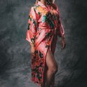 Lange koraalrode satijnen kimono met bloemenprint en ceintuur, hoge split aan de zijkant.