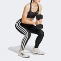 Een vrouw in een zwarte sportbeha en zwarte legging met witte strepen, squatend met een dumbbell.