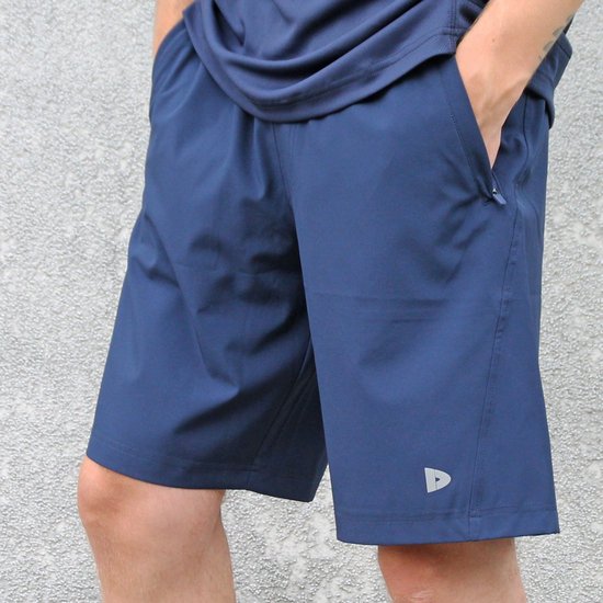Dichtbij opname van een donkerblauwe sportshort met zakken en Donnay logo.