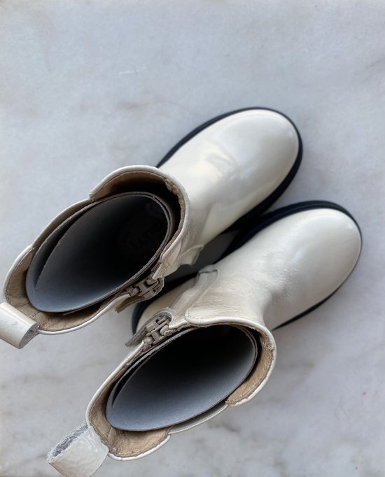 Binnenkant van glanzende witte lakleren chelsea boots, met rits en grijze binnenzool.
