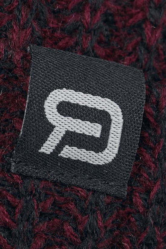 Detail van een grijs logo-label met een wit logo op een bordeauxrode en zwarte gebreide muts.