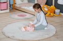 Meisje op een rond kleed kleedt een baby pop aan. Baby Annabell.