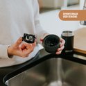 Une personne démonte le couvercle d'un thermos Kambukka noir.