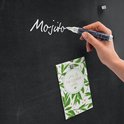 Hand schrijft "Mojito" met een witte glasbordmarker op een zwart bord, met een kaartje ernaast.
