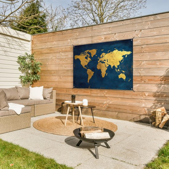Carte du monde dorée sur fond bleu foncé, accrochée à une clôture en bois dans un jardin avec un salon de jardin.