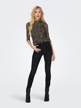 Model met blonde haren draagt een coltrui met panterprint en zwarte skinny jeans.