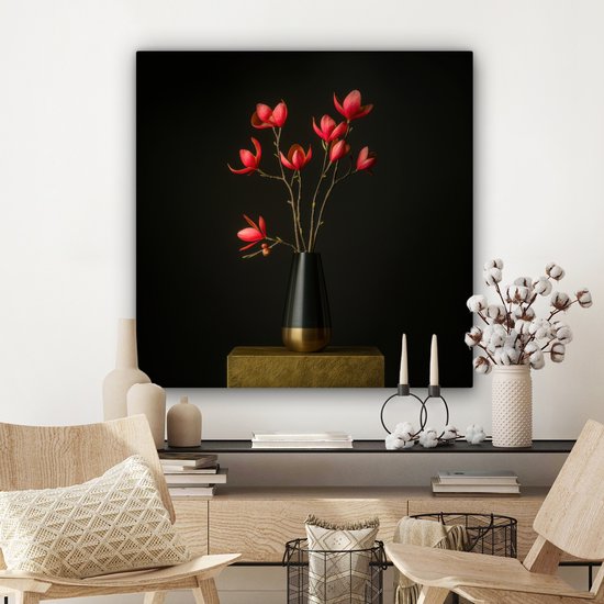 Rode bloemen in een zwarte vaas op een gouden sokkel, in een interieur met een commode en stoelen.