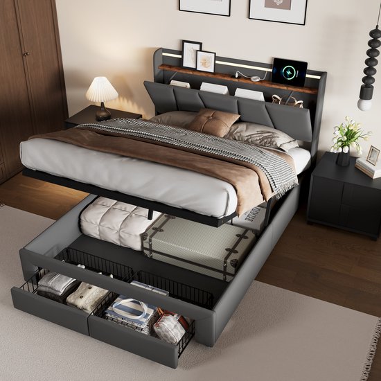Donkergrijs bed met open gasveer-opslag vol koffers en kleding. Lades aan de voet met kleding.