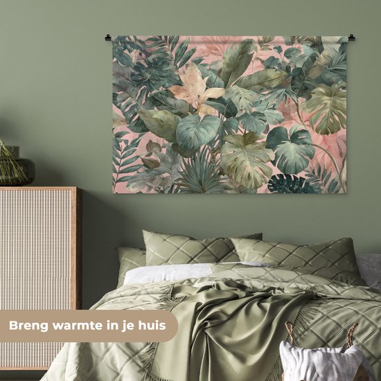 Een wandkleed met een tropische bladerenprint in groen en roze, hangend boven een groen bed in een slaapkamer.
