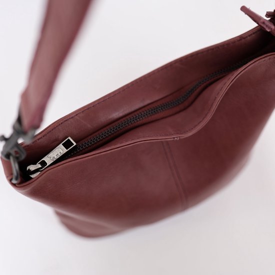 Bordeauxrode leren tas met rits en zilverkleurige ritslip met logo.
