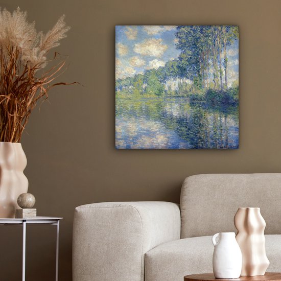 Tableau de Claude Monet: Peuples au bord de l'Epte, suspendu à un mur brun au-dessus d'un canapé beige.