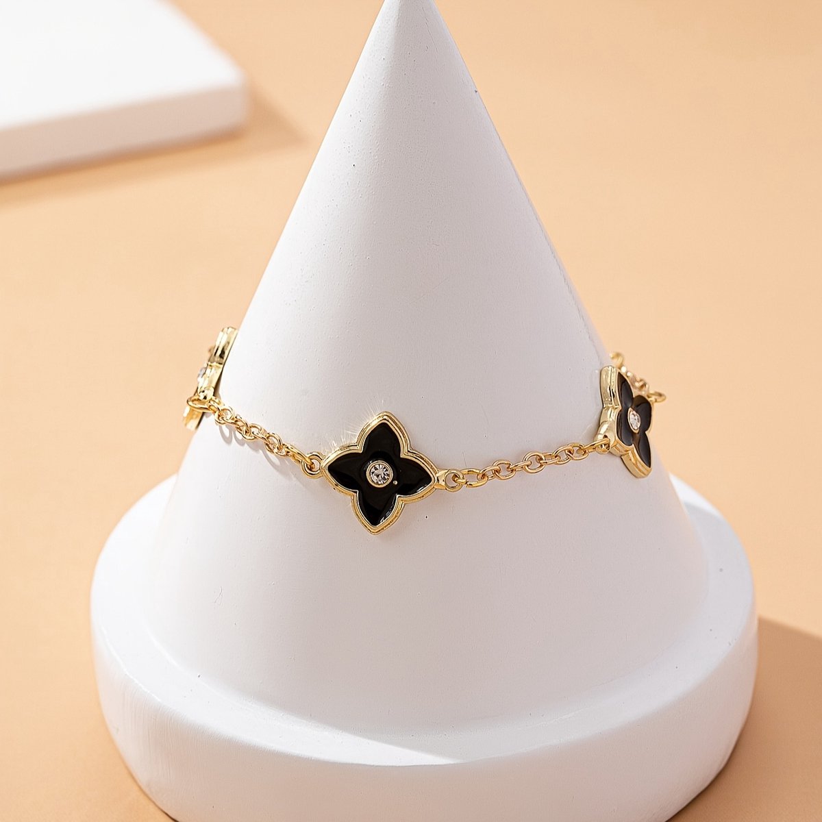 Sjika - Gold plated armband met zwarte klaver bloemen – Luxe damesarmband met kristalaccent – Trendy & Elegant sieraad – Perfect cadeau voor haar