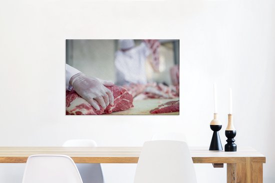 Le boucher découpe la viande en morceaux de toile 60x40 cm - Tirage photo sur toile (Décoration murale salon / chambre)
