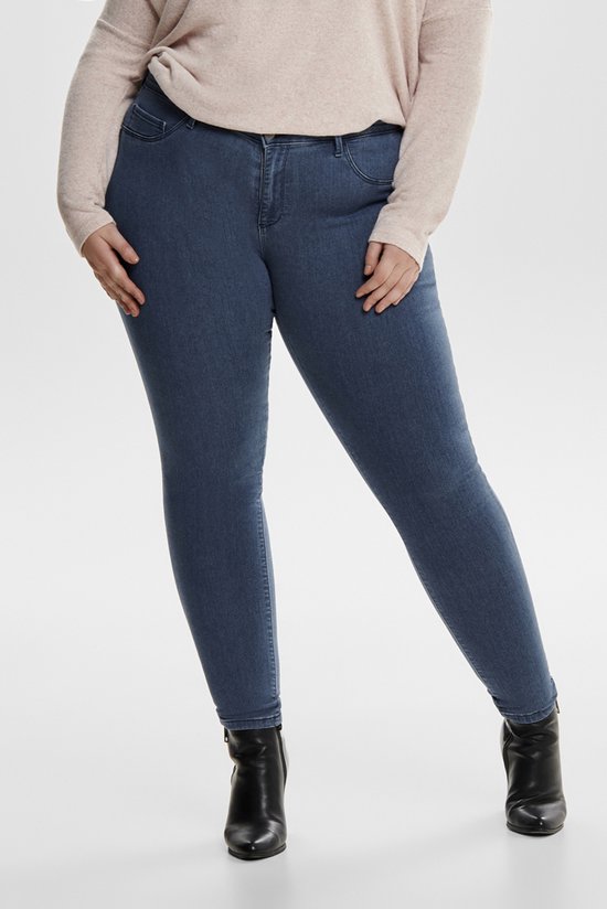 Blauwe skinny jeans, voorkant. Model draagt een lichtroze trui en zwarte enkellaarsjes.