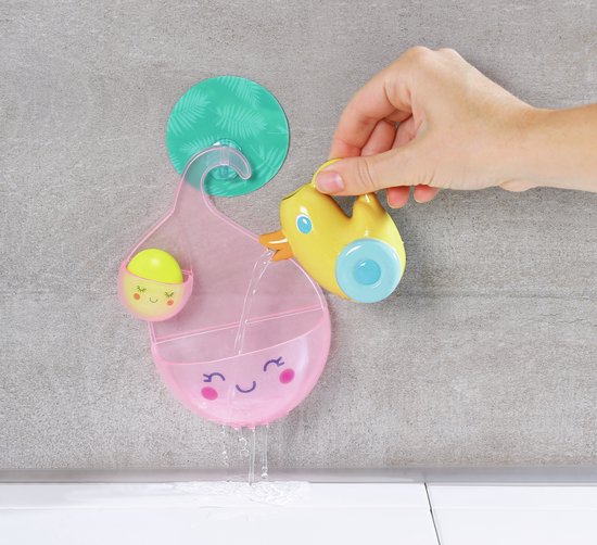 Hand vult roze beker met water via gele badeend. Water loopt door beker. Beker hangt aan haak.