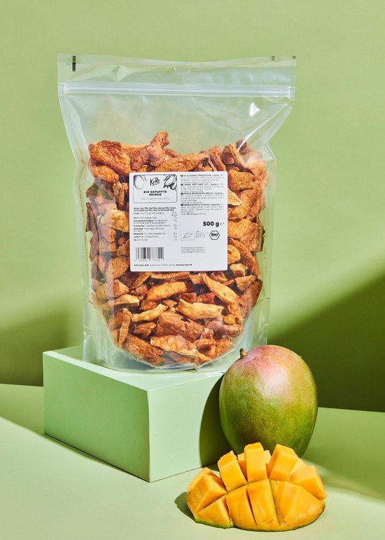 Een zak gepofte biologische mango op een lichtgroene sokkel met een verse mango ernaast.