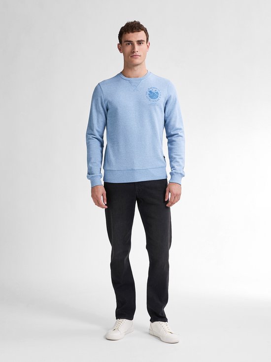 Model in zwarte, rechte jeans en lierblauwe sweater met print op de borst.
