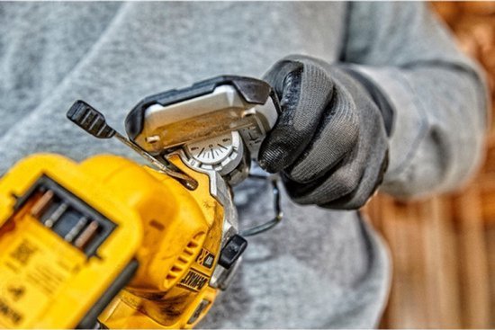 Een hand met een DeWalt handschoen draait aan een instelknop op een gele en zwarte decoupeerzaag.