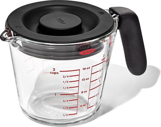 Glazen maatbeker met deksel en zwart handvat. Rode ml- en cup-markeringen zichtbaar.