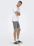 Man met witte T-shirt en grijze denim shorts met omgeslagen broekspijpen, zijaanzicht.