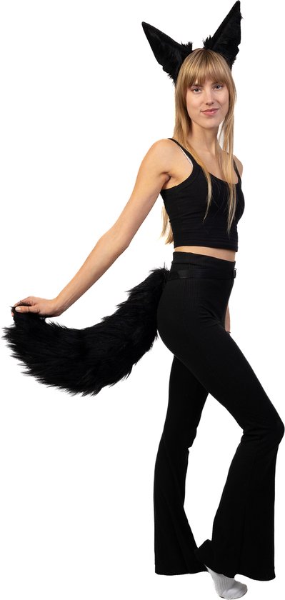 Vrouw met blonde haren, zwarte top, broek, harige staart en dierenoortjes, die naar links kijkt.