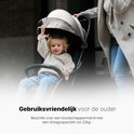 Een kind op een zwarte buggy, een vrouw loopt erachter.
