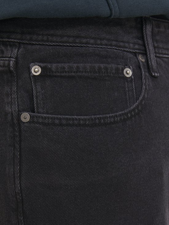 Close-up van de voorkant van een zwarte jeans met een klein zakje.