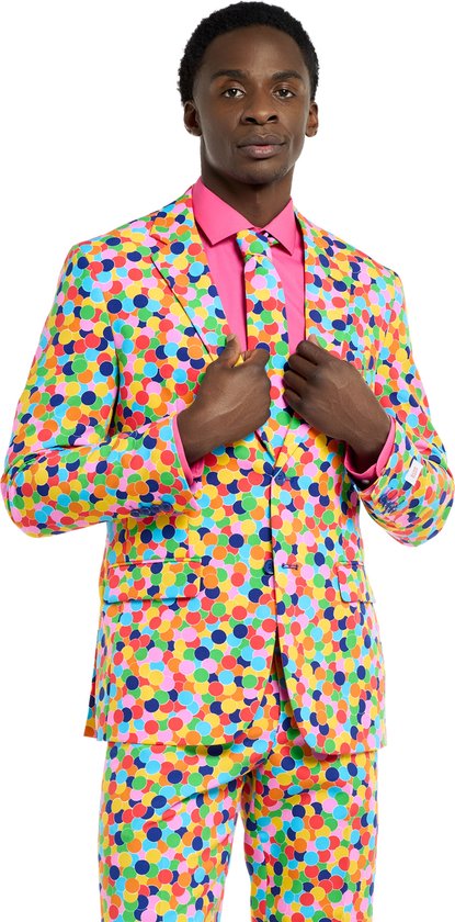 Man in een veelkleurig pak met confettiprint en roze shirt.