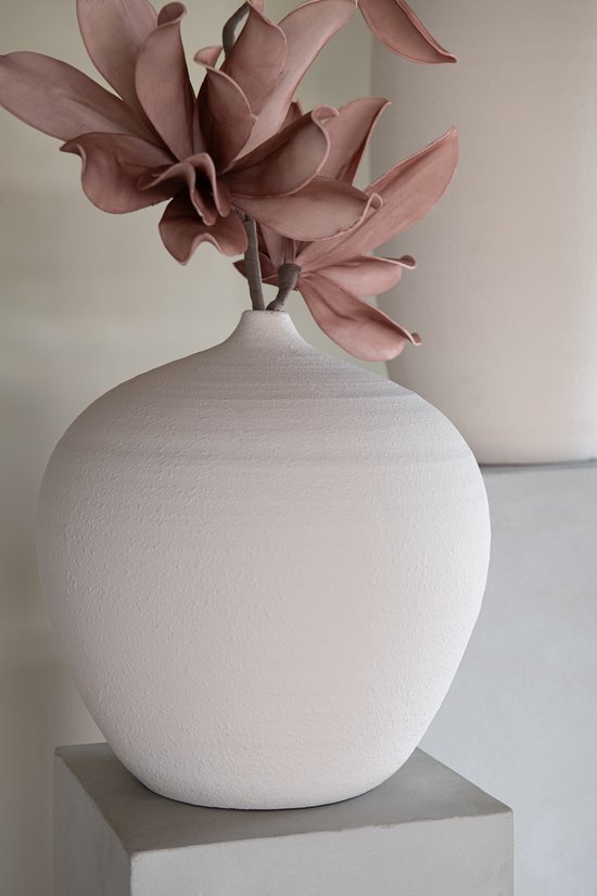 Witte, ronde vaas met een gespannen, getextureerd oppervlak, met een tak met roze bloemen.