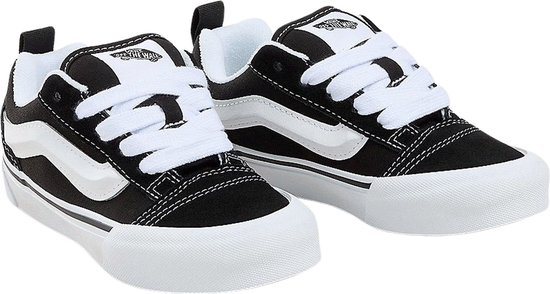 Paar zwarte Vans sneakers met witte strepen, witte zolen en witte veters.