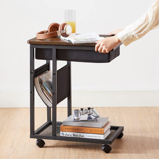 Zijtafel met houten blad, een zwarte stoffen mand, metalen frame en wieltjes. Een hand sluit het opbergvak.