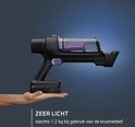 Handzame kruimeldief, zwart met transparante stofcontainer, in een hand gehouden.