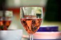 Een close-up van een glas rosé met bubbels en rode glinsteringen.