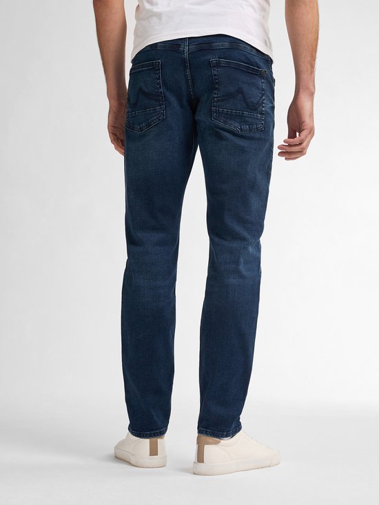 Achterkant van een man in een donkerblauwe, slimfit jeans met zes zakken en merkdetail op de rechterzak.