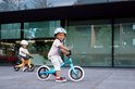 Twee kinderen met helmen op fietsen buiten, op de voorgrond een blauwe fiets.