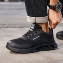 Zwarte lage werksneakers met veters, ademend mesh en stevige zool. 'NEZR SAFETY' logo op de zijkant.