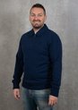 Homme portant un sweat bleu foncé à col zippé, un jean et le logo Fred Perry.