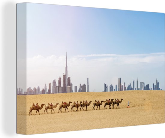 Canvas Schilderij Kudde kamelen in de woestijn en op de achtergrond de Burj Khalifa en Dubai - 120x80 cm - Wanddecoratie
