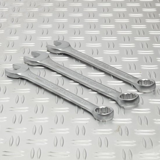 Drie zilverkleurige ring-steeksleutels op een gebogen metalen ondergrond.