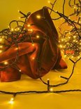 Warme LED-lichtjes op een donkere kabel, deels gewikkeld rond een rode stof.