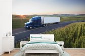 Behang - Fotobehang Vrachtwagen rijdend in een groene omgeving - Breedte 420 cm x hoogte 280 cm