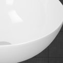 Détail du bord d'un lavabo rond en céramique blanche.