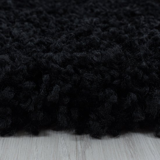 Zwart hoogpolig shaggy vloerkleed met een zachte textuur, close-up.