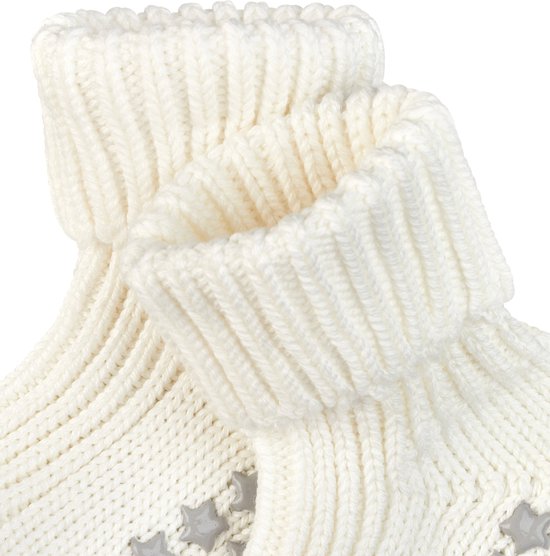 Detailopname van de zachte, gebreide witte babysokjes met omslagboord en anti-slip sterretjes.