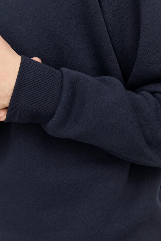 Close-up van de mouw van een donkerblauwe sweater met geribde manchetten.