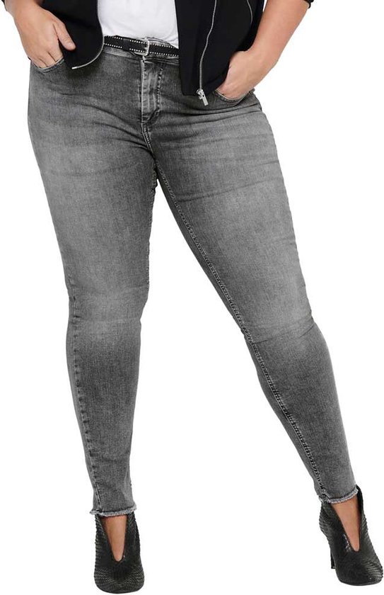Model in grijze skinny jeans met rafelige zoom, riem en zwarte laarsjes.