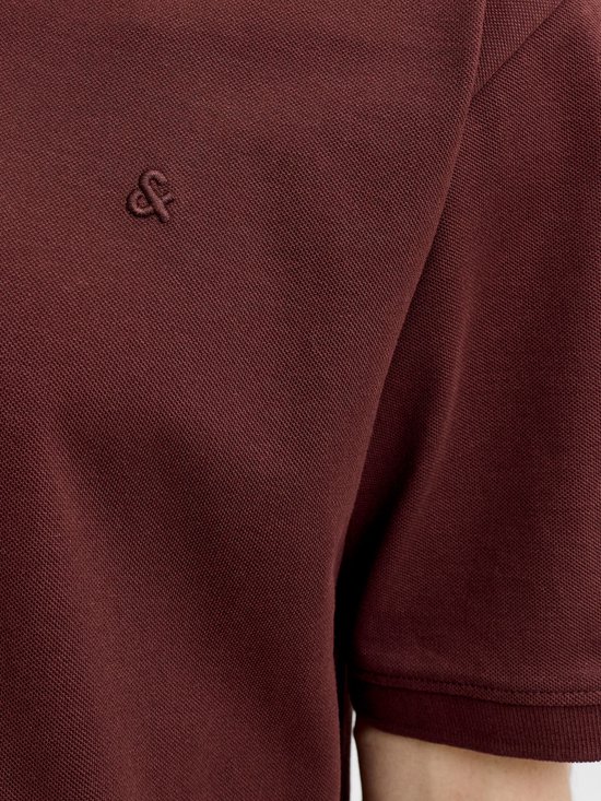 Detail van het geborduurde logo op een donkerbruine polo