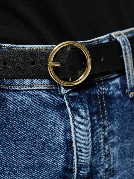Zwarte riem met goudkleurige gesp, gedragen met een spijkerbroek.